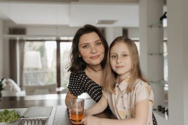 Smiling mother and daughter enjoying quality time in a stylish kitchen.