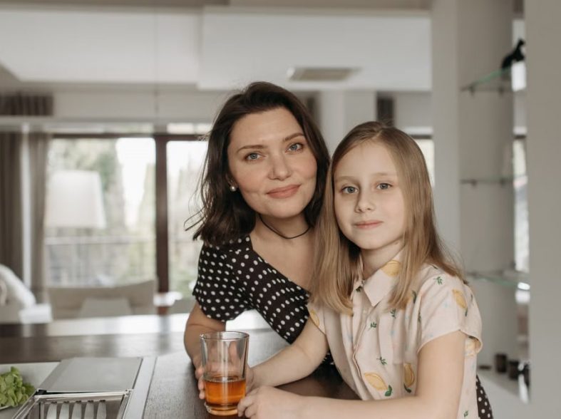 Smiling mother and daughter enjoying quality time in a stylish kitchen.